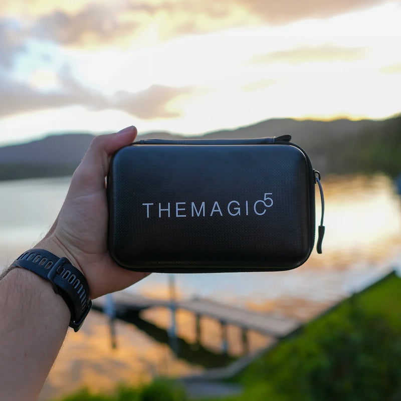 The magic 5 goggle case held in hand witha a scenery background with lake and mountains