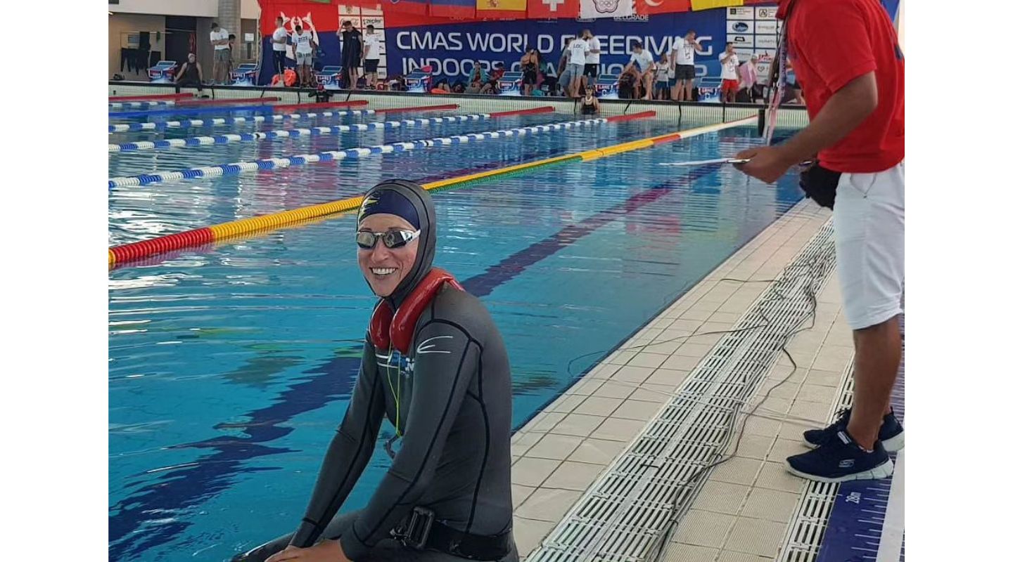 Katie sitting beside the pool in her competition suit and Magic5 goggles.