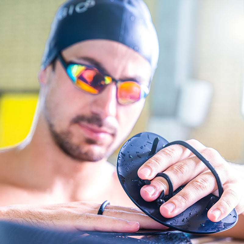 Athlete adjusting finger paddles for swim training and stroke technique improvement